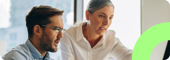 Two people collaborating and looking at a computer monitor.