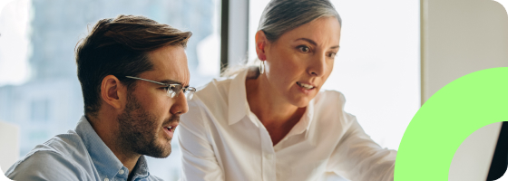 Two people collaborating and looking at a computer monitor.