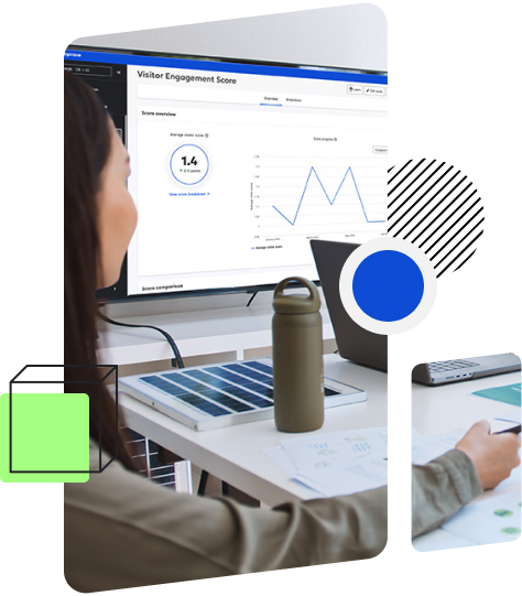 A person is sitting at a desk looking at a monitor displaying a 'Visitor Engagement Score' screen with graphs and data.